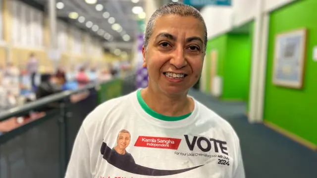 Kamla Sangha wears a white campaign t-shirt with a message saying "Vote Kamla Sangha Independent".