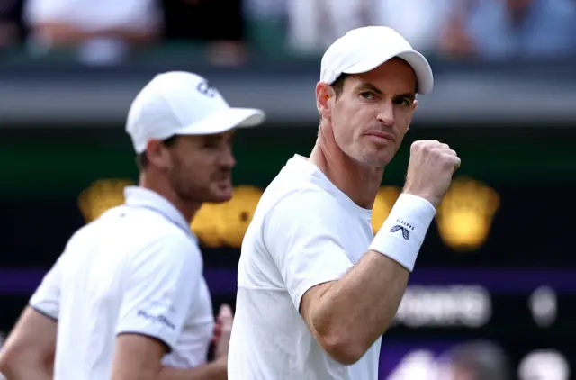 Andy Murray clenches his fist in celebration with Jamie Murray out of focus in the background