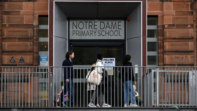 Three people enter Notre Dame Primary School