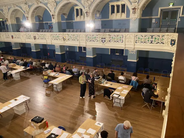 Counters behind desks and others waiting for ballots to arrive at Oxford Town Hall for the Oxford East count