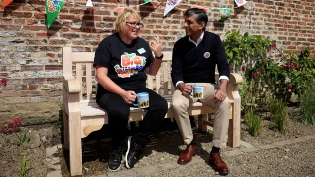 A woman and a man sit on a bench talking