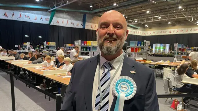 Eddie McDonald with white hair and beard and a large rosette at the Kettering count