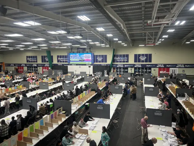 Ballot papers being counted at long tables at the Mattioli Arena in Leicester