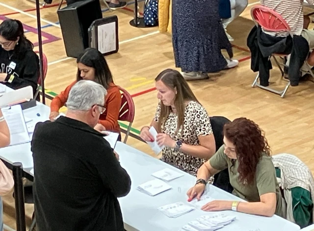 Three women counting votes at the Bracknell count