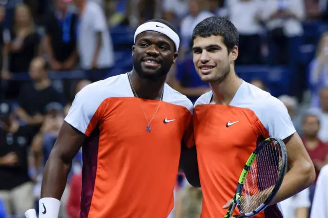 Frances Tiafoe and Carlos Alcaraz pose for a photo at the net at the start of their US Open 2022 semi-final, wearing matching Nike tops