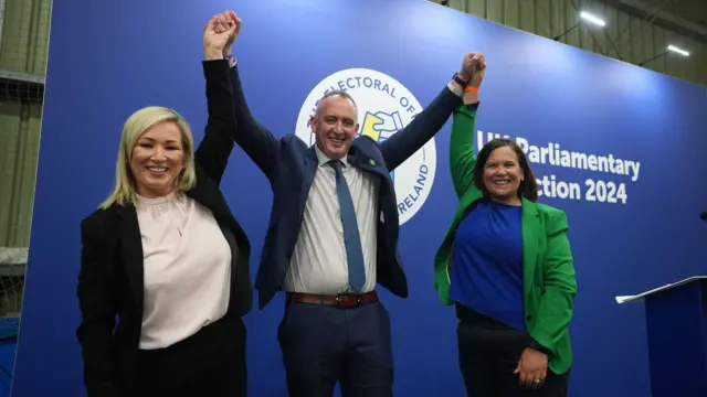 Sinn Féin MP for Mid Ulster Cathal Mallaghan, centre of the photo, as Michelle O'Neill holds up his right arm and Mary Lou McDonald holds up his left arm