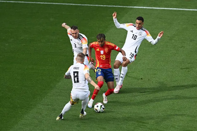 Lamine Yamal of Spain runs with the ball whilst under pressure from Toni Kroos, David Raum and Jamal Musiala