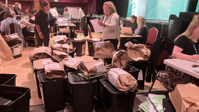 Ballot boxes being allocated to tables for counting