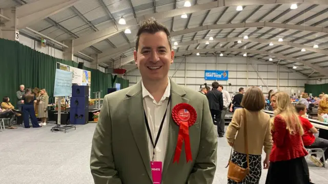 Mike Reader with short dark hair and red rosette