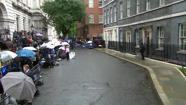 Media stand on Downing Street with umbrellas