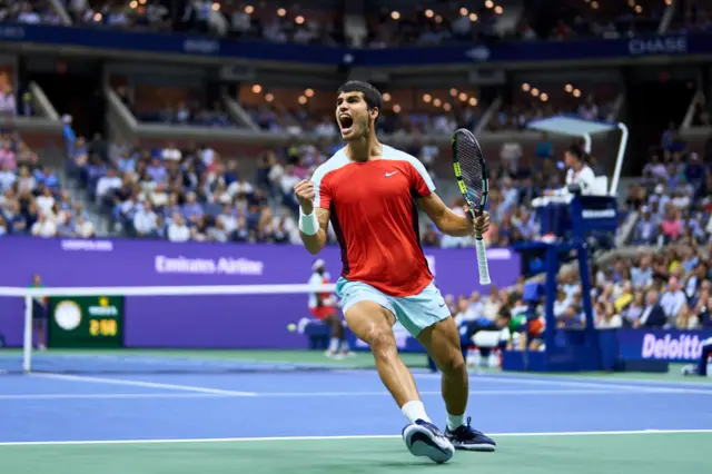 Carlos Alcaraz roars in celebration and pumps his fist as he turns away from the court and looks to the crowd