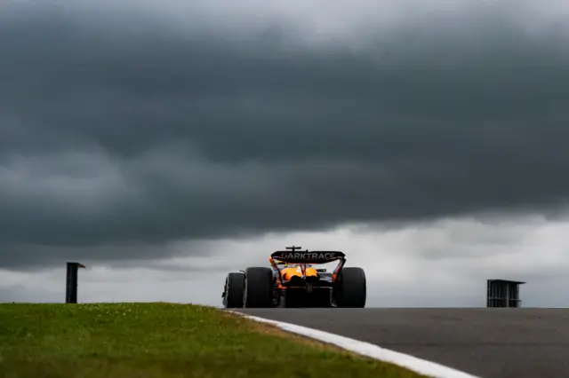 Oscar Piastri on track at Silverstone beneath dark clouds