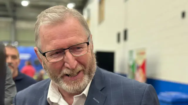 UUP leader Doug Beattie smiling, with a blurred background of the Magherafelt count centre