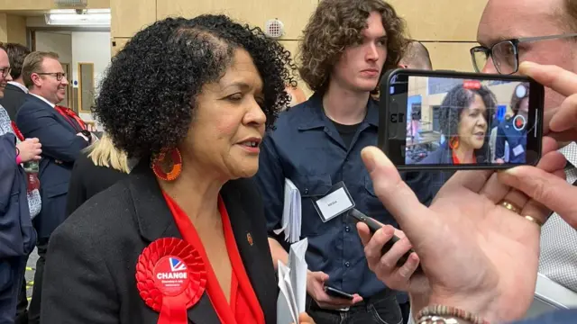 A woman speaks to a reporter