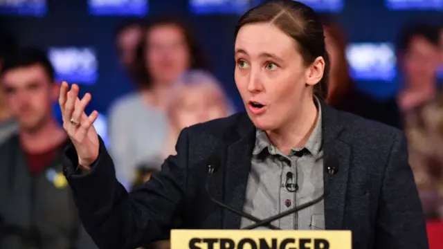 Mhairi Black gestures as she stands at a podium while giving a speech