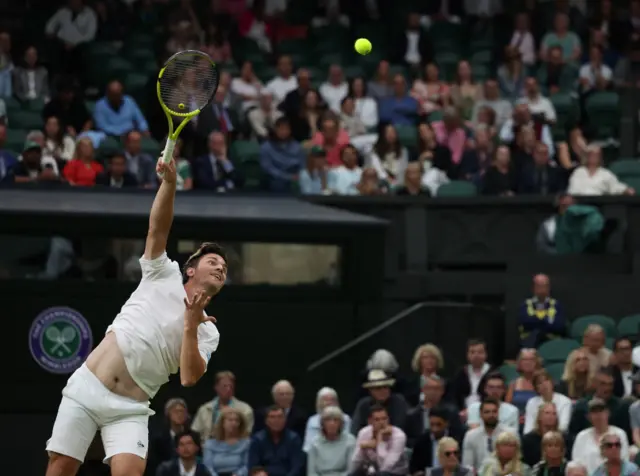 Miomir Kecmanovic serves with the Centre Court crowd in the background