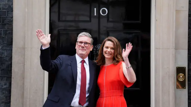 Keir Starmer and his wife Vic wave in front of the Downing Street door