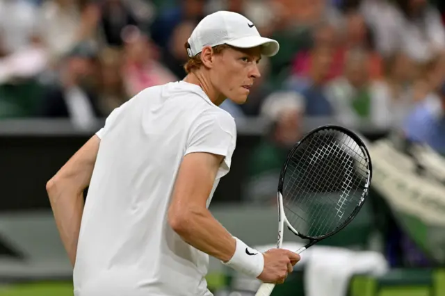 Jannik Sinner shakes his racquet in celebration