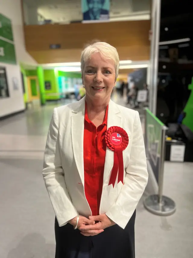 Labours Karin Smyth wearing a red rosette smiles for the camera