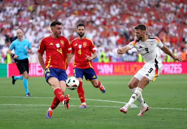 Niclas Fuellkrug of Germany shoots whilst under pressure from Aymeric Laporte