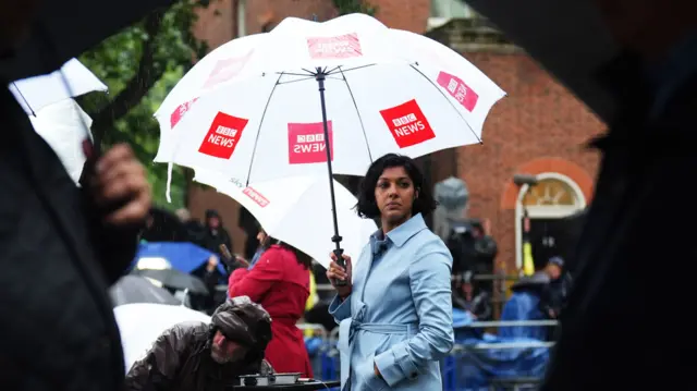 Leila Nathoo holds a BBC umbrella in the rain in Downing Street