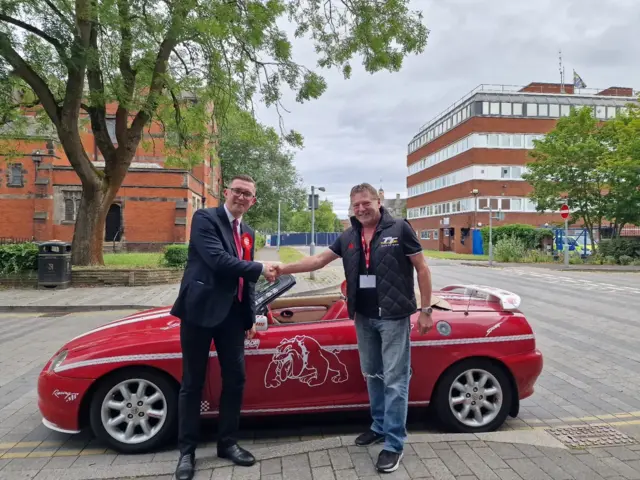 Connor Naismith with a constituent and a sports car