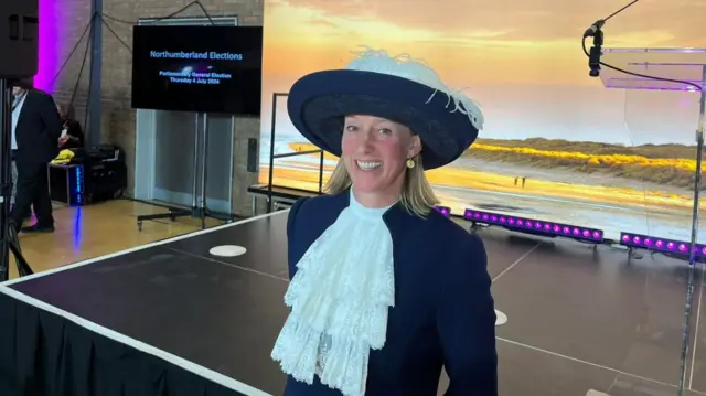 Lucia Bridgeman, High Sheriff of Northumberland, smiling at the camera, wearing a navy blue hat with white feathers