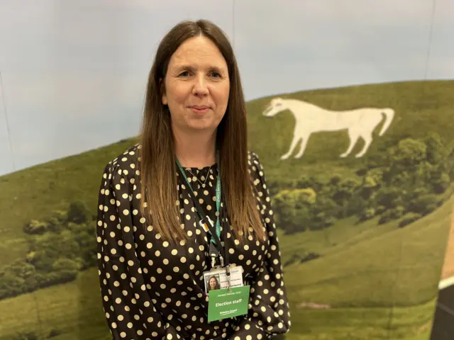 Lucy Townsend standing in front of a banner of the Westbury White Horse