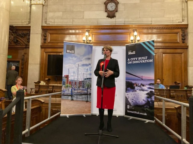 Emma Hardy standing in front of a microphone dressed in red