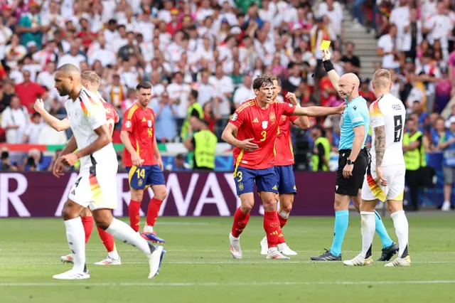 Robin Le Normand of Spain receives a yellow card from Referee Anthony Taylor