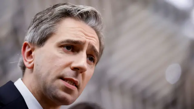 A close up of Simon Harris from the shoulders up, to the left of the frame