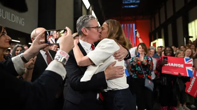 Britain's Labour Party leader Keir Starmer kisses his wife Victoria with a crowd taking pictures around them during a victory rally at the Tate Modern in London