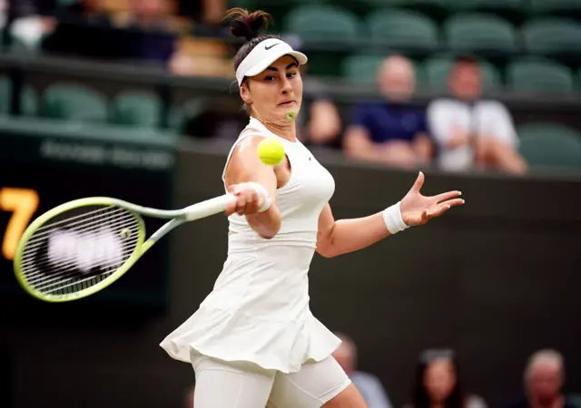 Bianca Andreescu hits a forehands wearing an all-white Nike dress and white Nike visor cap