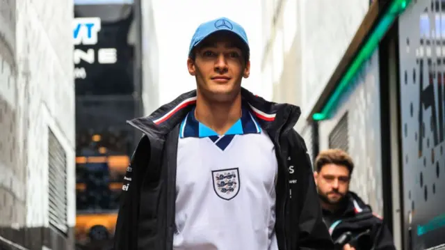 Formula 1 driver George Russell arrives for qualifying at the 2024 British Grand Prix wearing an England football jersey