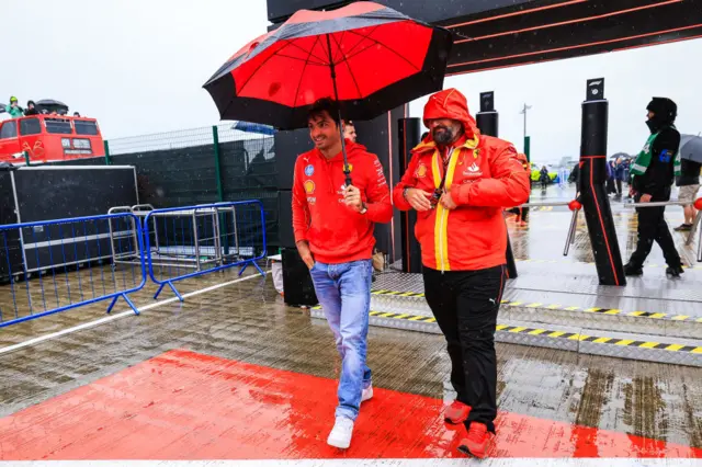 Carlos Sainz arrives under an umbrella to Silverstone