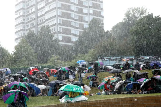 Fans shelter under umbrellas on the Hill