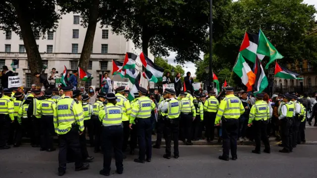 Police officers stand guard, as demonstrators attend a protest in solidarity with Palestinians in Gaza,