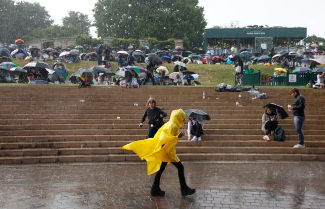 Fans shelter under umbrellas on the Hill