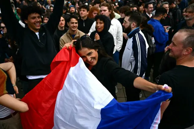 Partcipants react - some with the French national flag - as they celebrate following the announcement of the projected results of the second round of France's crunch legislative elections during a rally in Nantes, western France on July 7, 2024