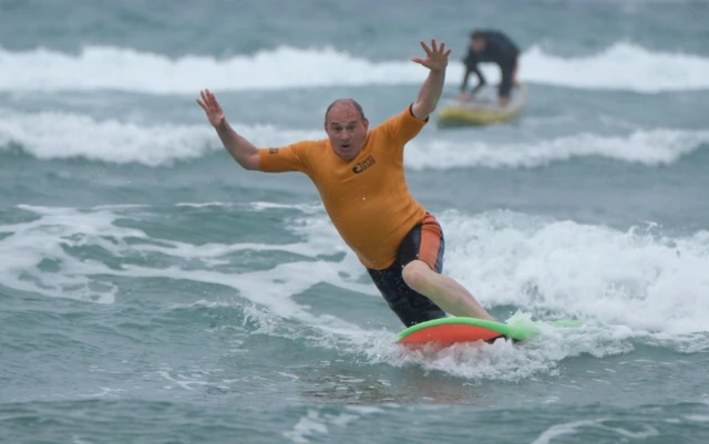 Sir Ed Davey falls from a surfboard during a visit to Big Blue Surf School in Bude in Cornwall