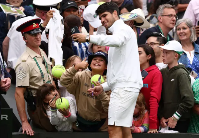 Carlos Alcaraz poses for a selfie with a young fan on Centre Court