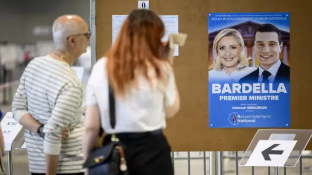 French people living in Switzerland look at an election poster showing French member of parliament Marine Le Pen (L) and French far right party National Rally (RN) leader Jordan Bardella