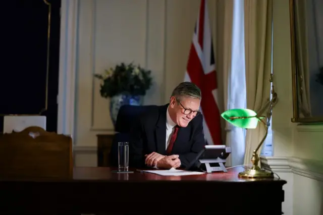 Starmer at a desk looking at a phone