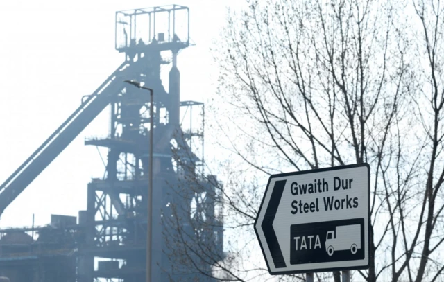 A sign is seen with Tata Steel Port Talbot steel production plant seen behind, ahead of its planned transition from blast furnace to electric arc furnaces, at Port Talbot, Wales