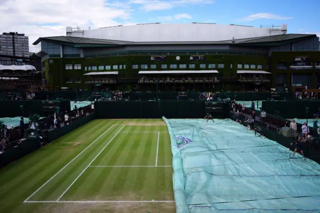 Groundstaff pull the covers off a court