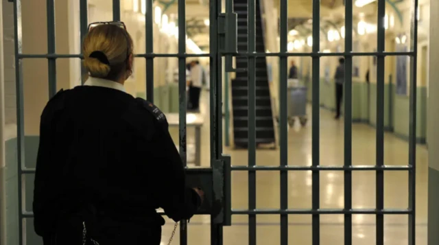 A prison officer locks up a door in a prison