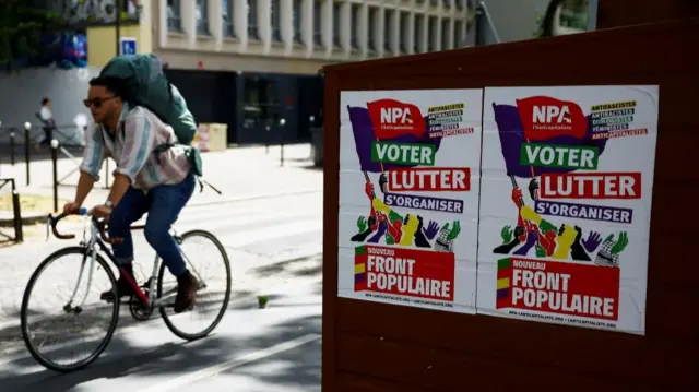 A man cycles near a campaign poster of the Anti-Capitalist Party (NPA), a member of the alliance of left-wing parties, called the "Nouveau Front Populaire" (New Popular Front - NFP) in Paris, France, July 6, 2024.