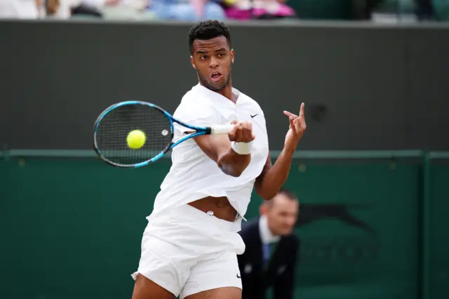 Giovanni Mpetshi Perricard hits a forehand shot wearing an all-white Nike top and white Nike shorts