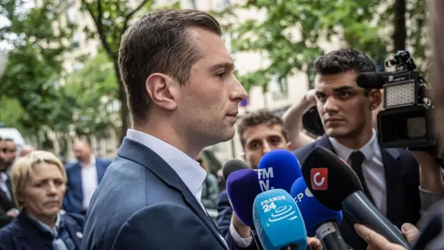 Side view shot of Jordan Bardella speaking into a microphone