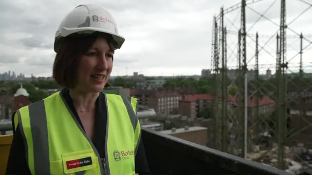 Chancellor Rachel Reeves in a hard hat and high vis jacket talking to the media at a construction site near the Oval, Kennington